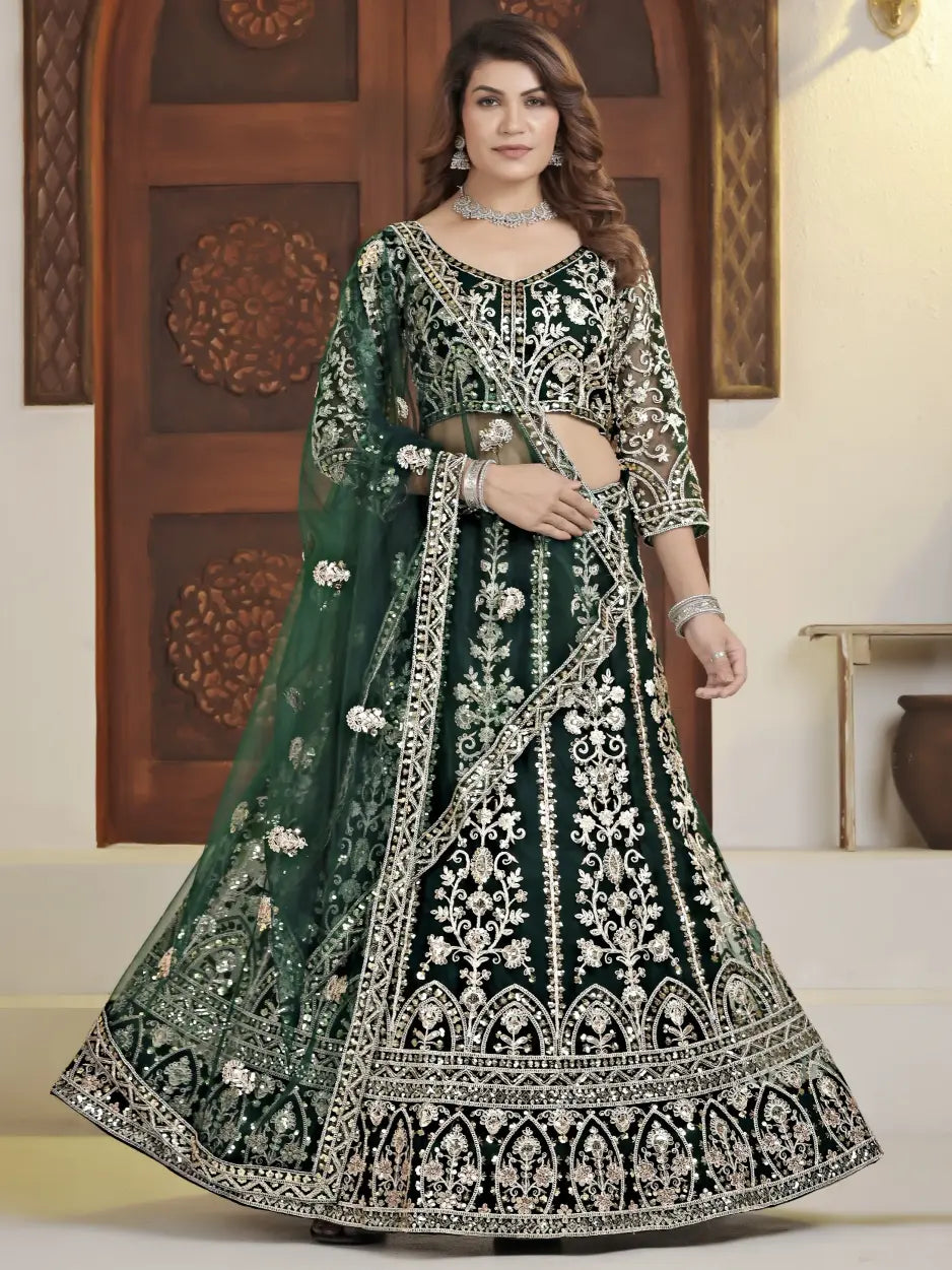 Woman wearing a green and black embroidered traditional outfit indoors.