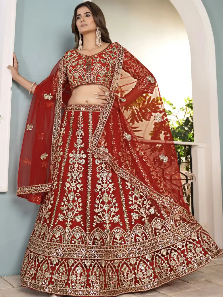 Woman wearing a red and gold embroidered traditional outfit indoors.