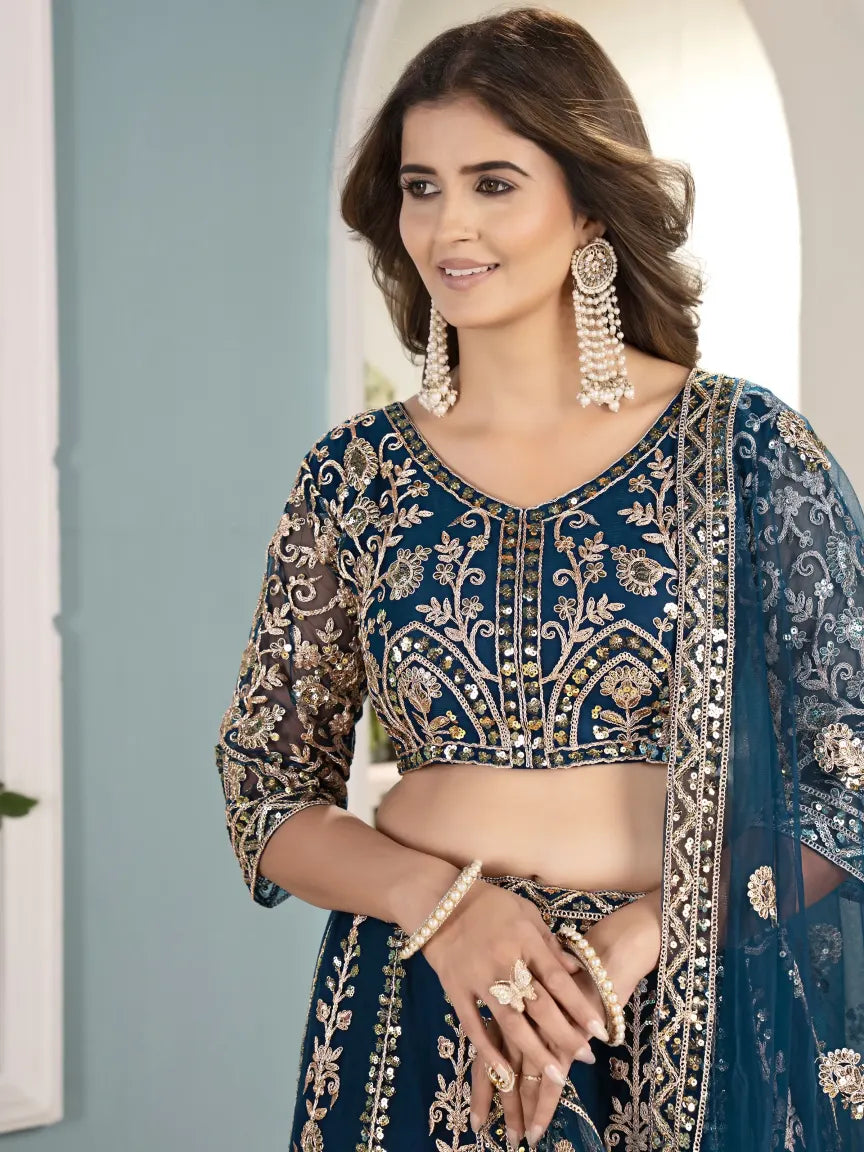 Woman wearing a blue embroidered traditional outfit with jewelry against a light background