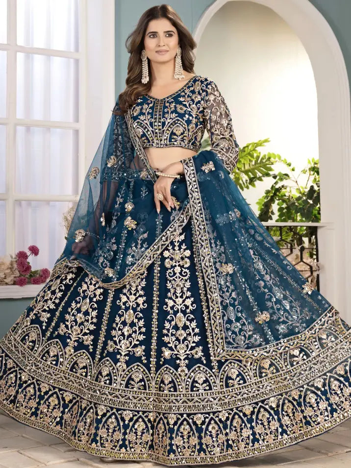 Woman wearing a blue embroidered traditional outfit indoors with a light background