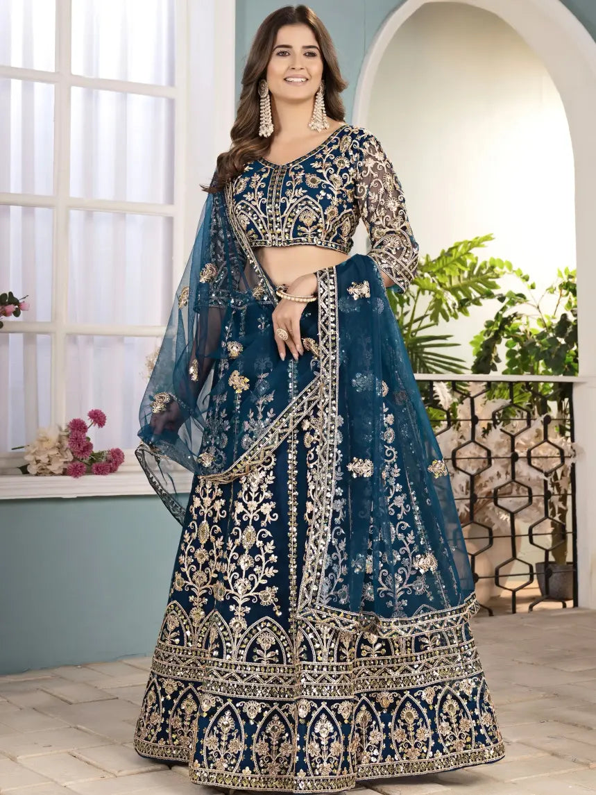 Woman wearing a traditional blue and gold embroidered outfit in an outdoor setting.