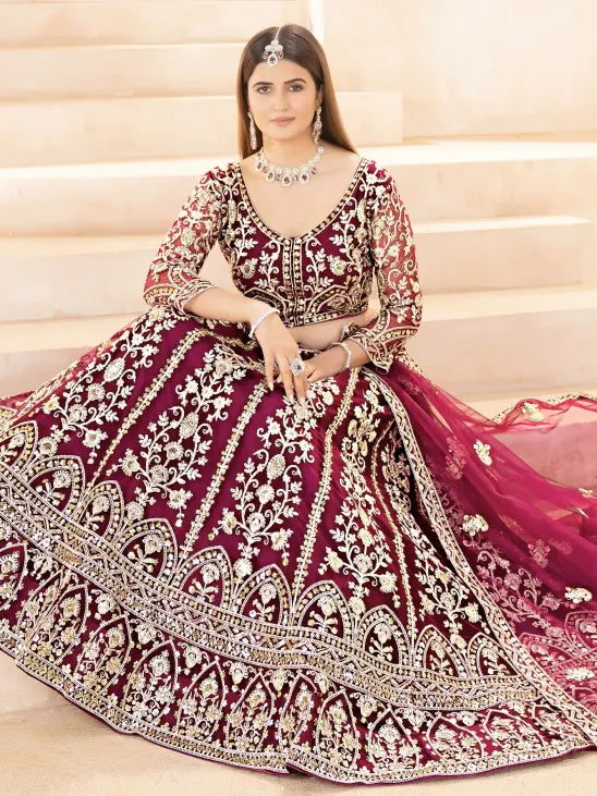 Woman wearing a maroon and gold embroidered traditional outfit on a beige background