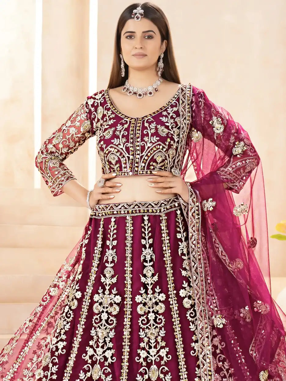 Woman wearing a traditional embroidered outfit with a pink dupatta against a neutral background