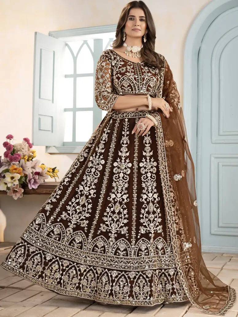 Woman wearing a brown and black embroidered traditional outfit with a light blue door and flowers in the background.