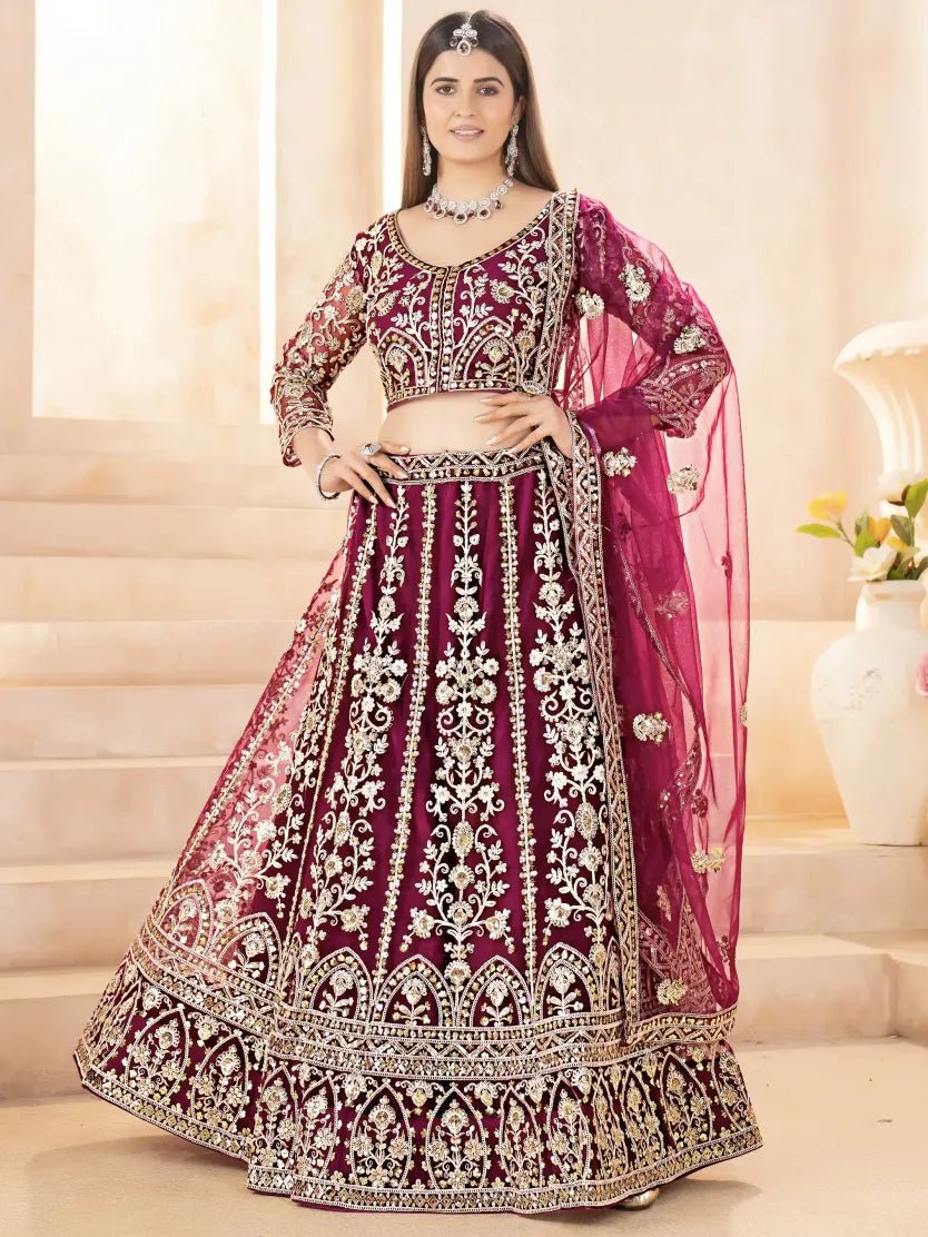Woman wearing a traditional embroidered purple and pink lehenga in an indoor setting.