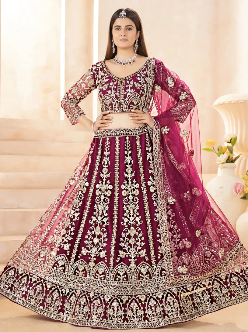 Woman wearing a traditional embroidered purple and pink lehenga with a white background