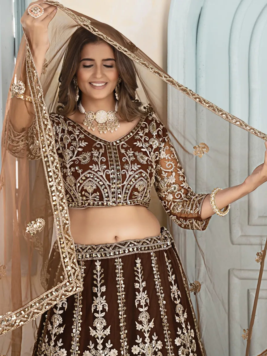 Woman wearing a brown and gold embroidered traditional outfit with a sheer dupatta.