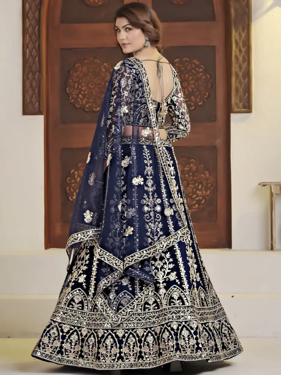 Woman wearing a traditional blue embroidered outfit with a decorative wooden door in the background