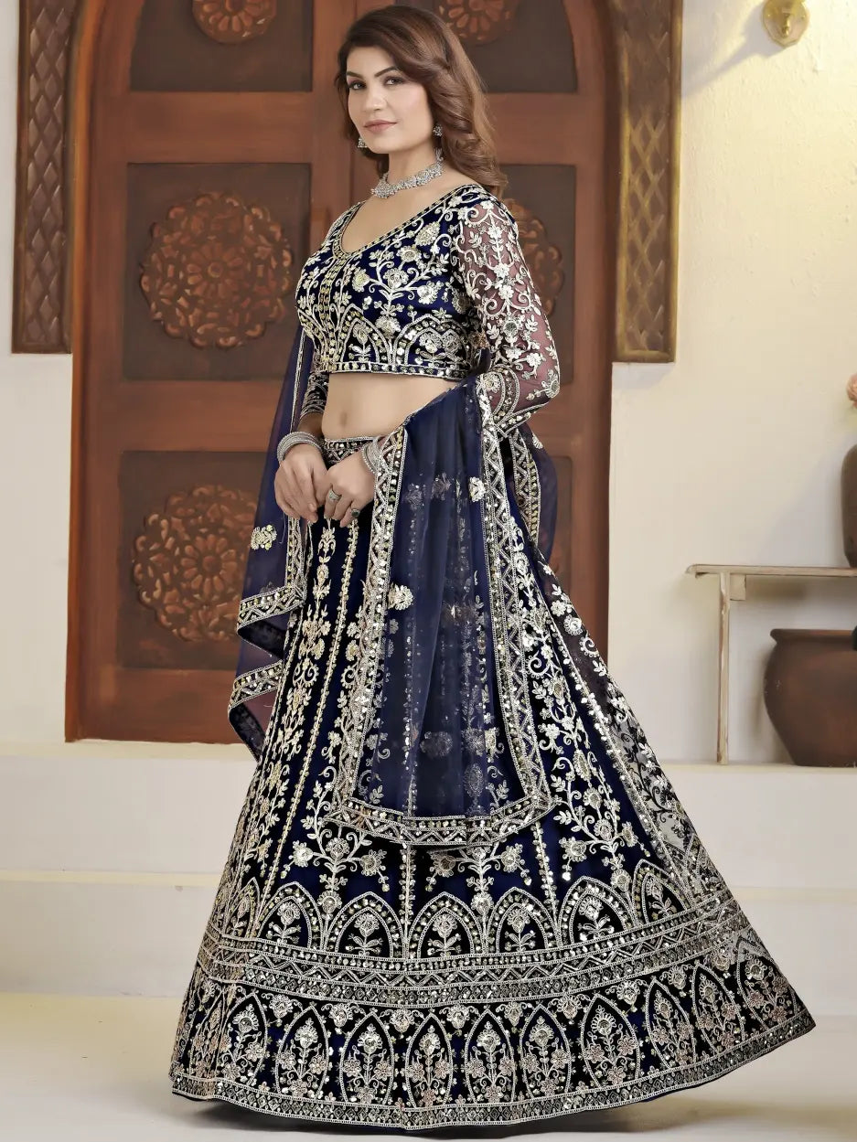 Woman wearing a traditional navy blue and white embroidered lehenga in an indoor setting.