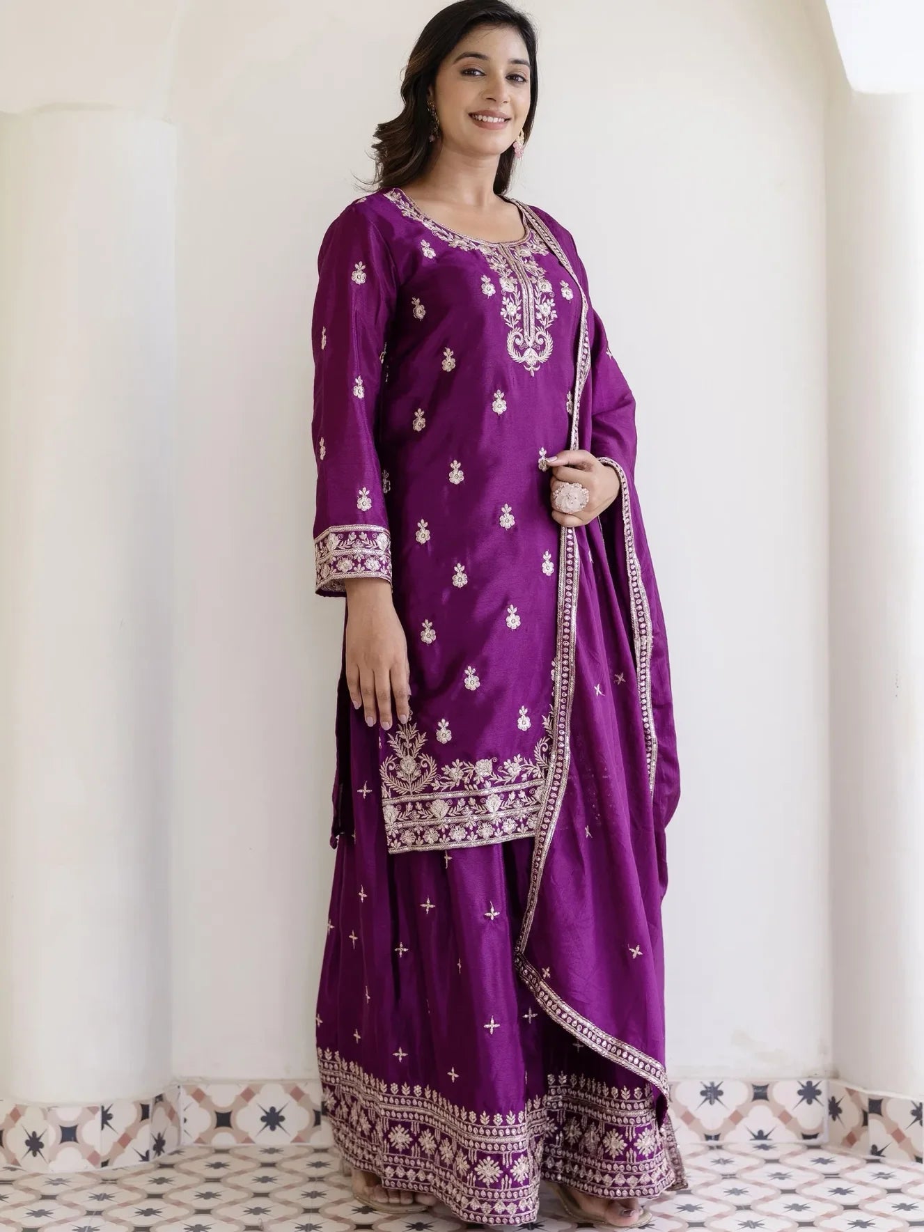 Woman wearing a purple traditional outfit with intricate designs on a white background
