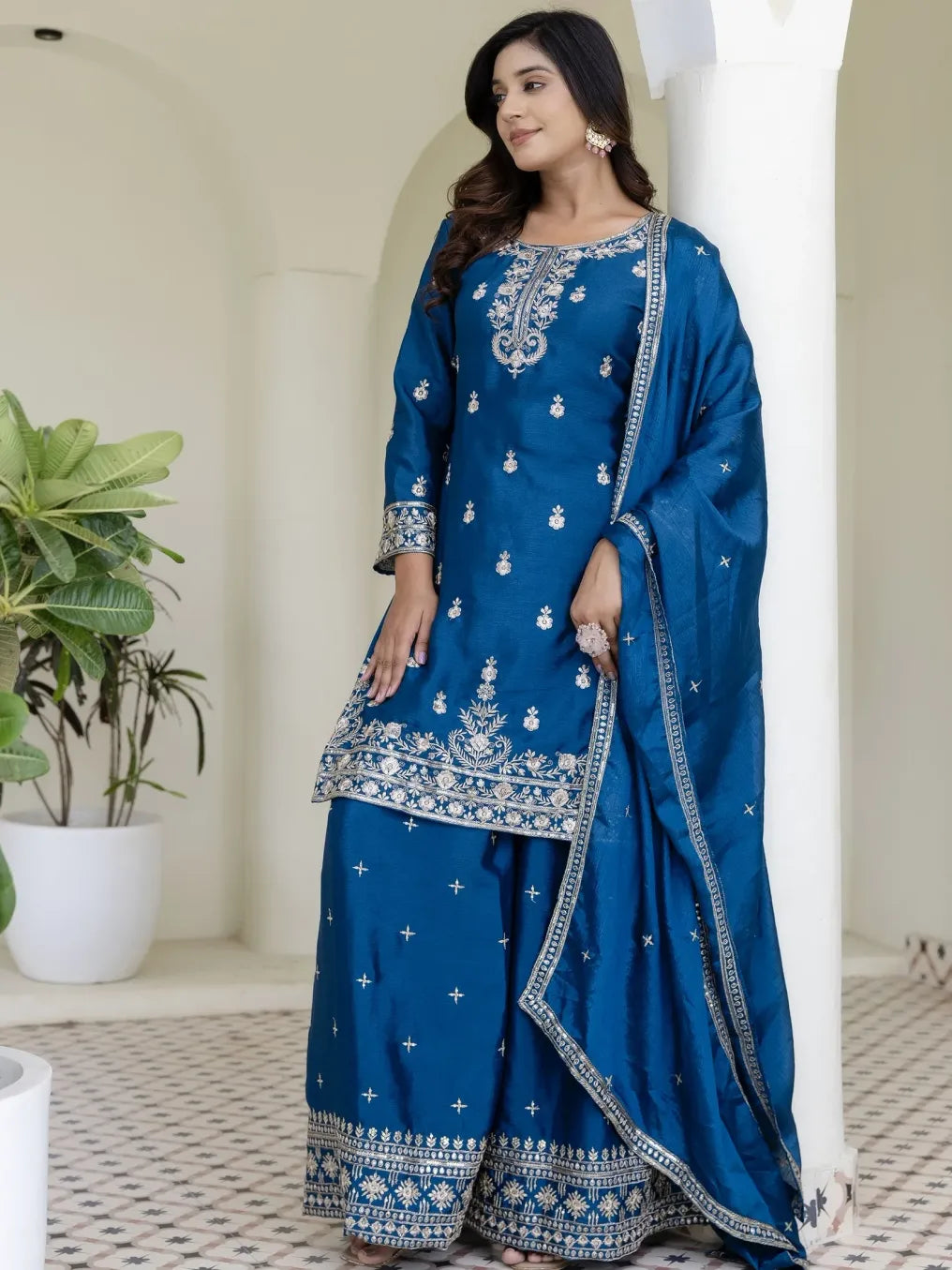 Woman wearing a blue embroidered saree with a white background