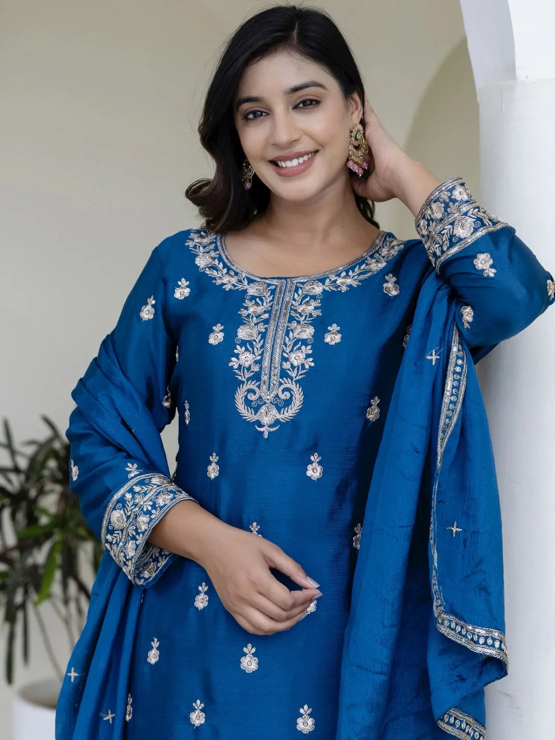 Woman wearing a blue embroidered traditional outfit with a white background