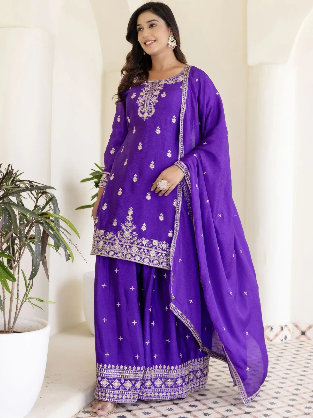 Woman wearing a purple embroidered traditional outfit with a white background