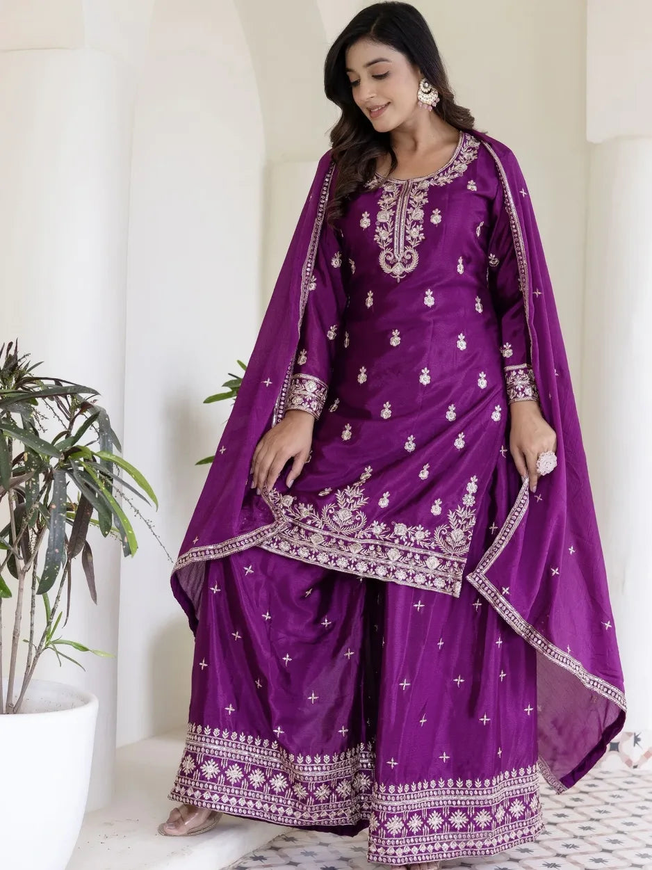 Woman wearing a purple traditional outfit with white embroidery against a white background