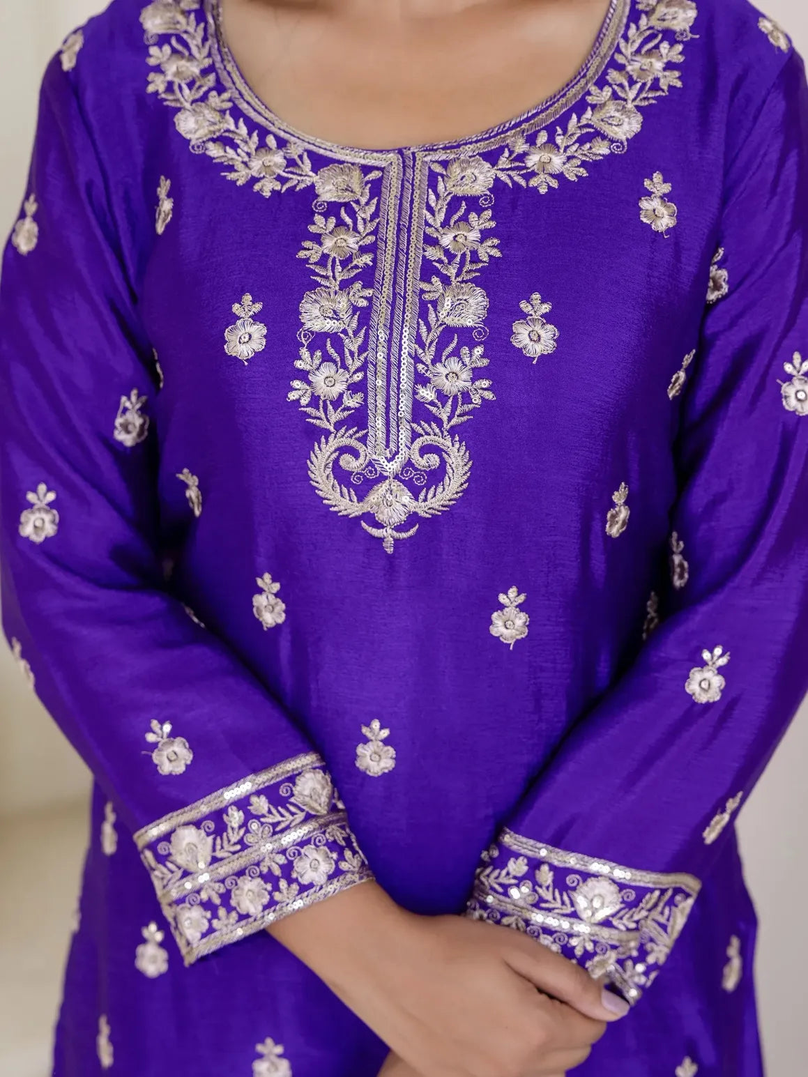 Purple embroidered garment with white patterns on a neutral background