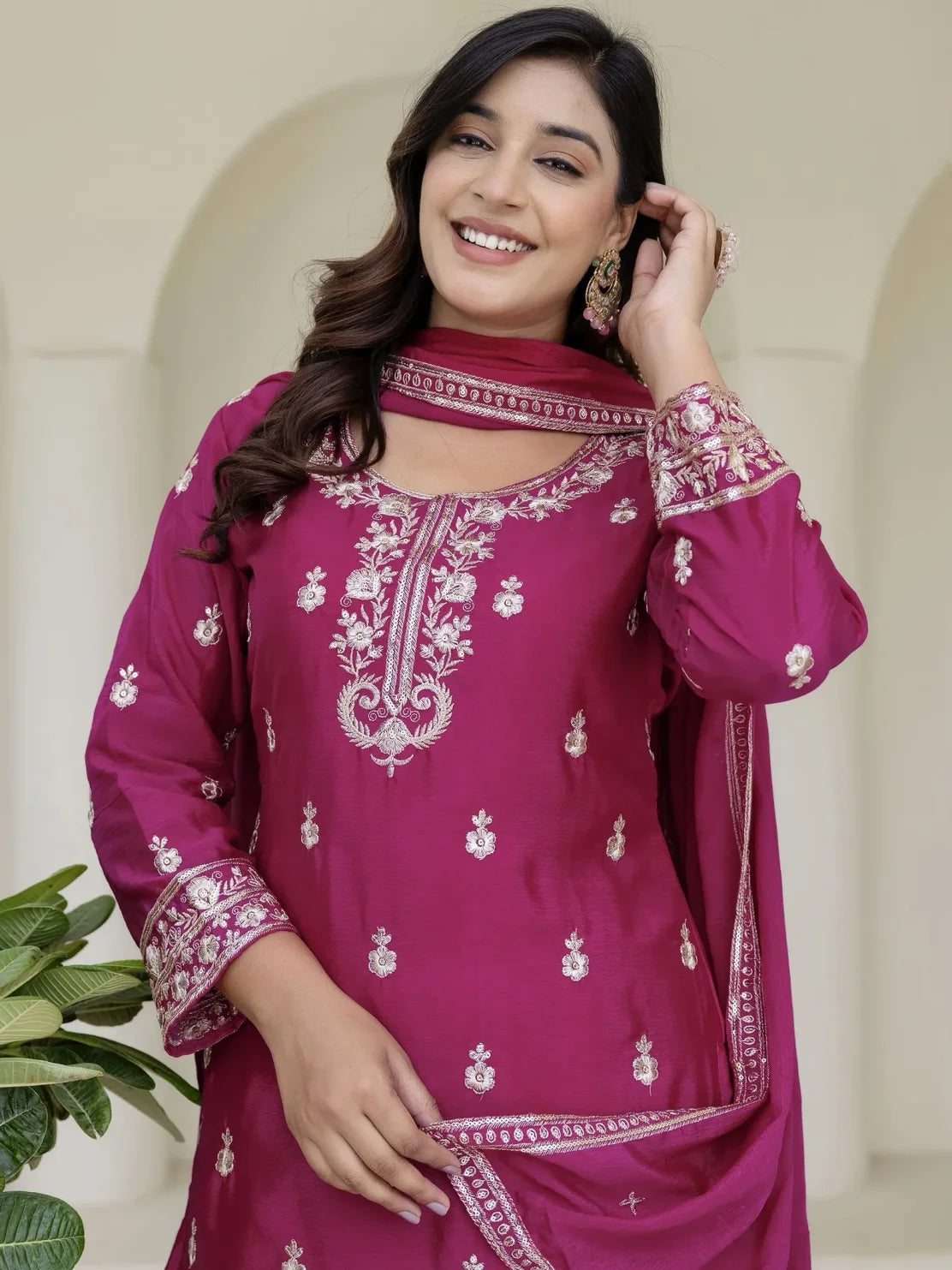 Woman wearing a pink embroidered traditional outfit with a neutral background