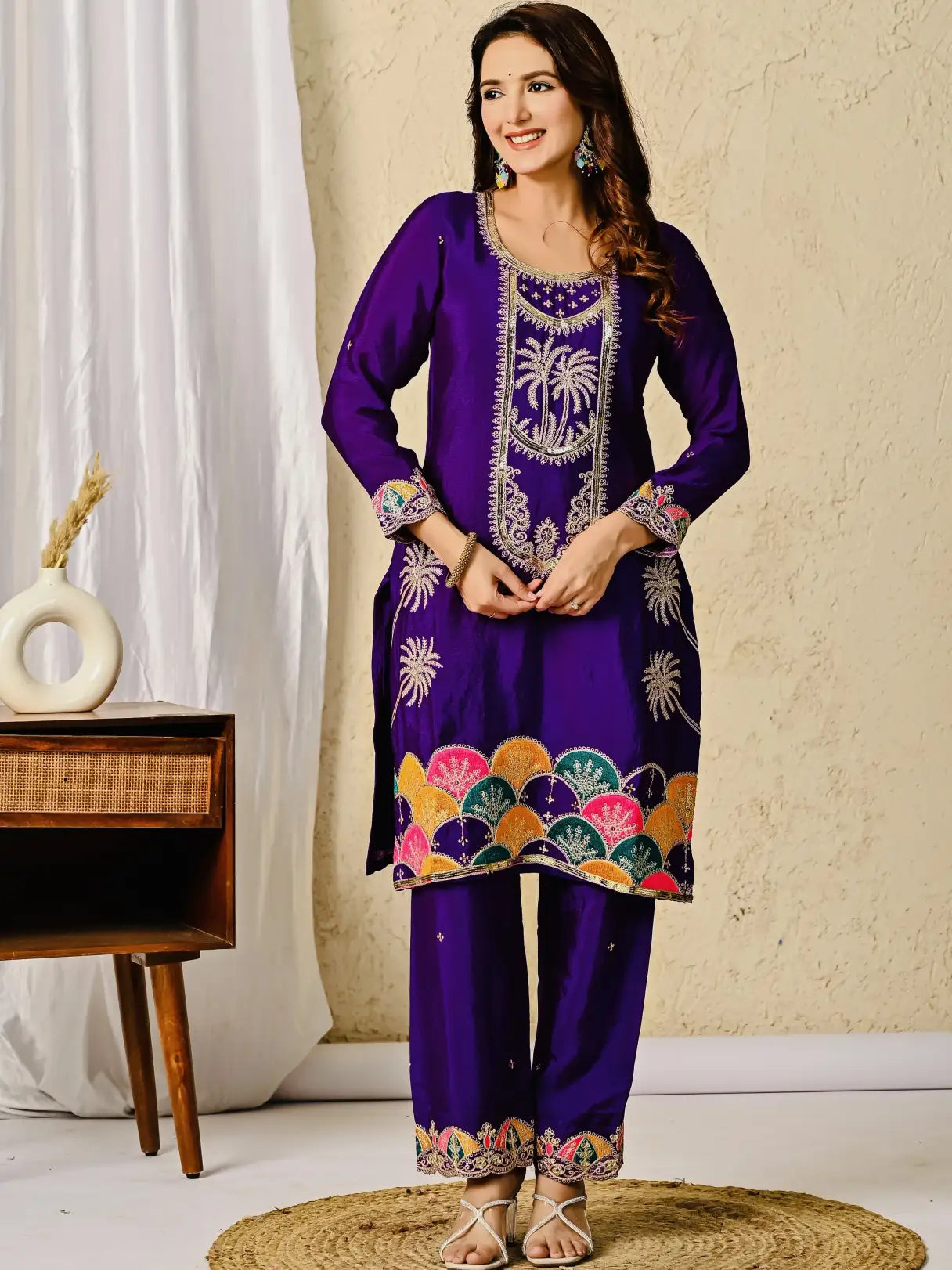 Woman wearing a purple embroidered traditional outfit with a decorative background