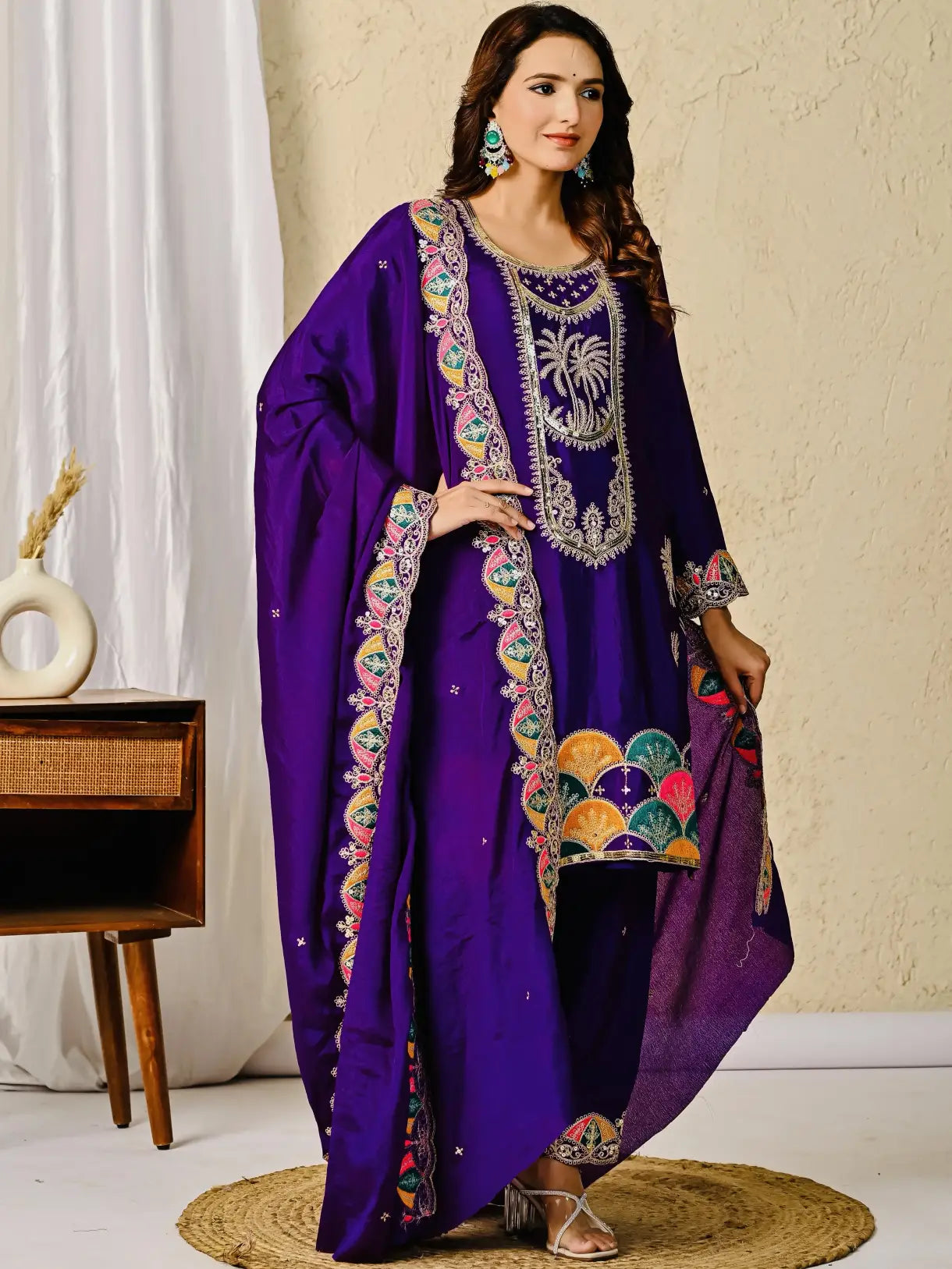 Woman wearing a purple embroidered traditional outfit indoors.