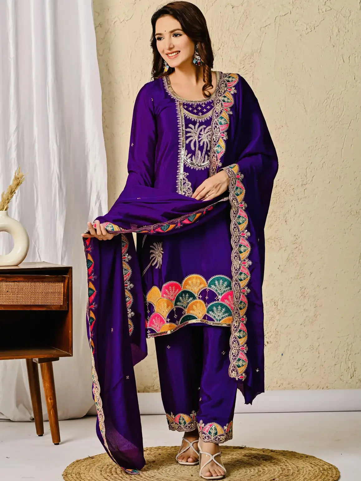 Woman wearing a purple embroidered traditional outfit with a plain background