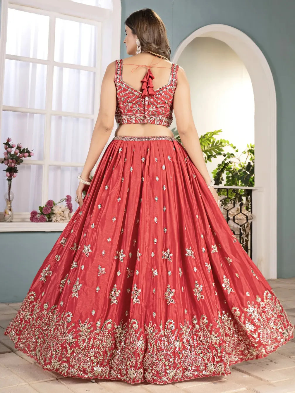 Woman wearing a red embroidered traditional outfit indoors.