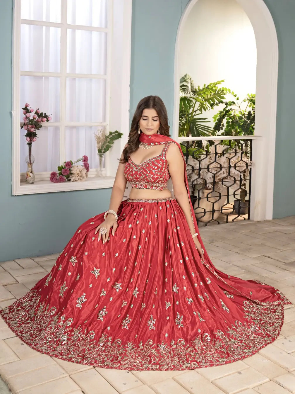 Woman in a red embroidered traditional outfit standing in a room with decorative elements.