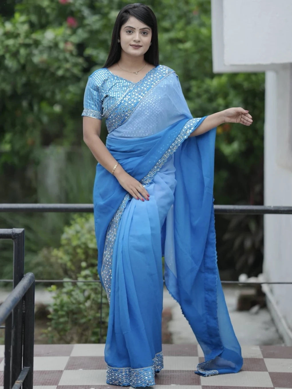 Woman wearing a blue saree with a blurred green background