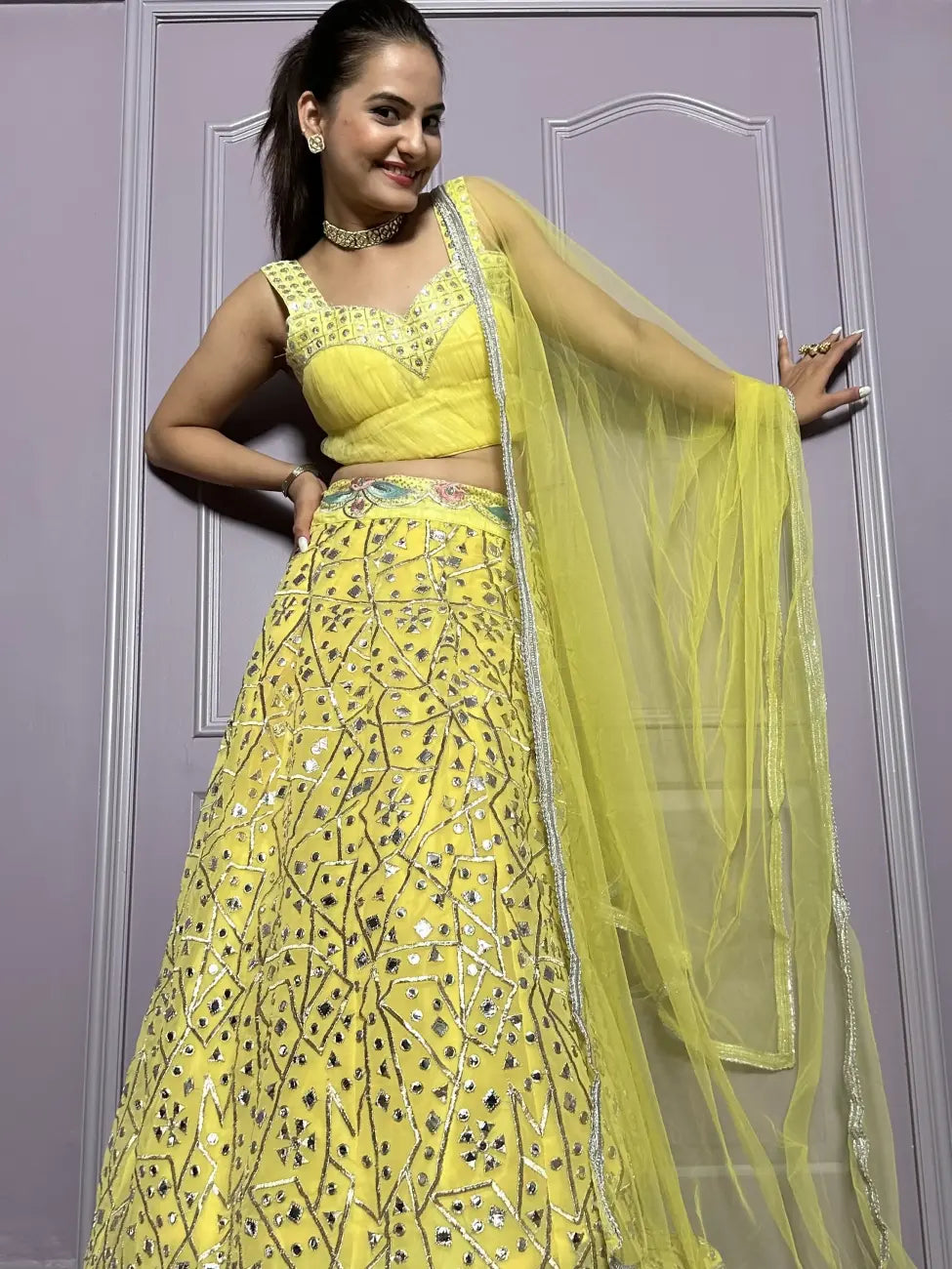 Woman wearing a yellow embroidered traditional outfit with a purple door background