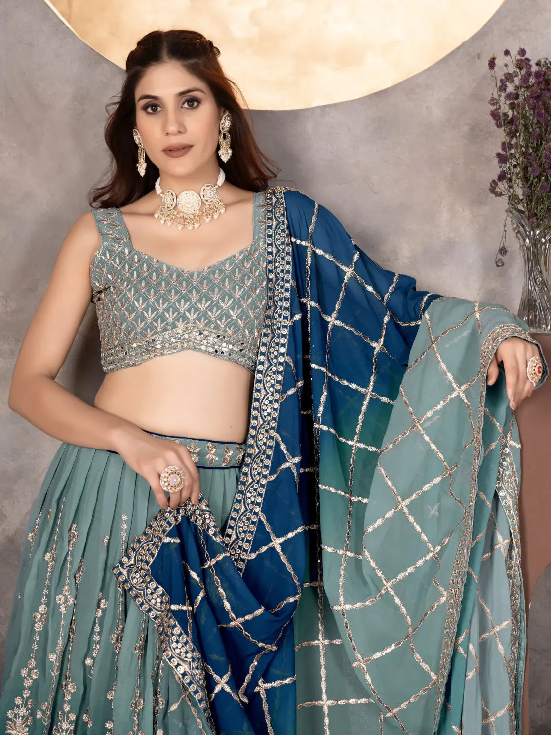 Woman in traditional outfit with blue and green saree against a neutral background