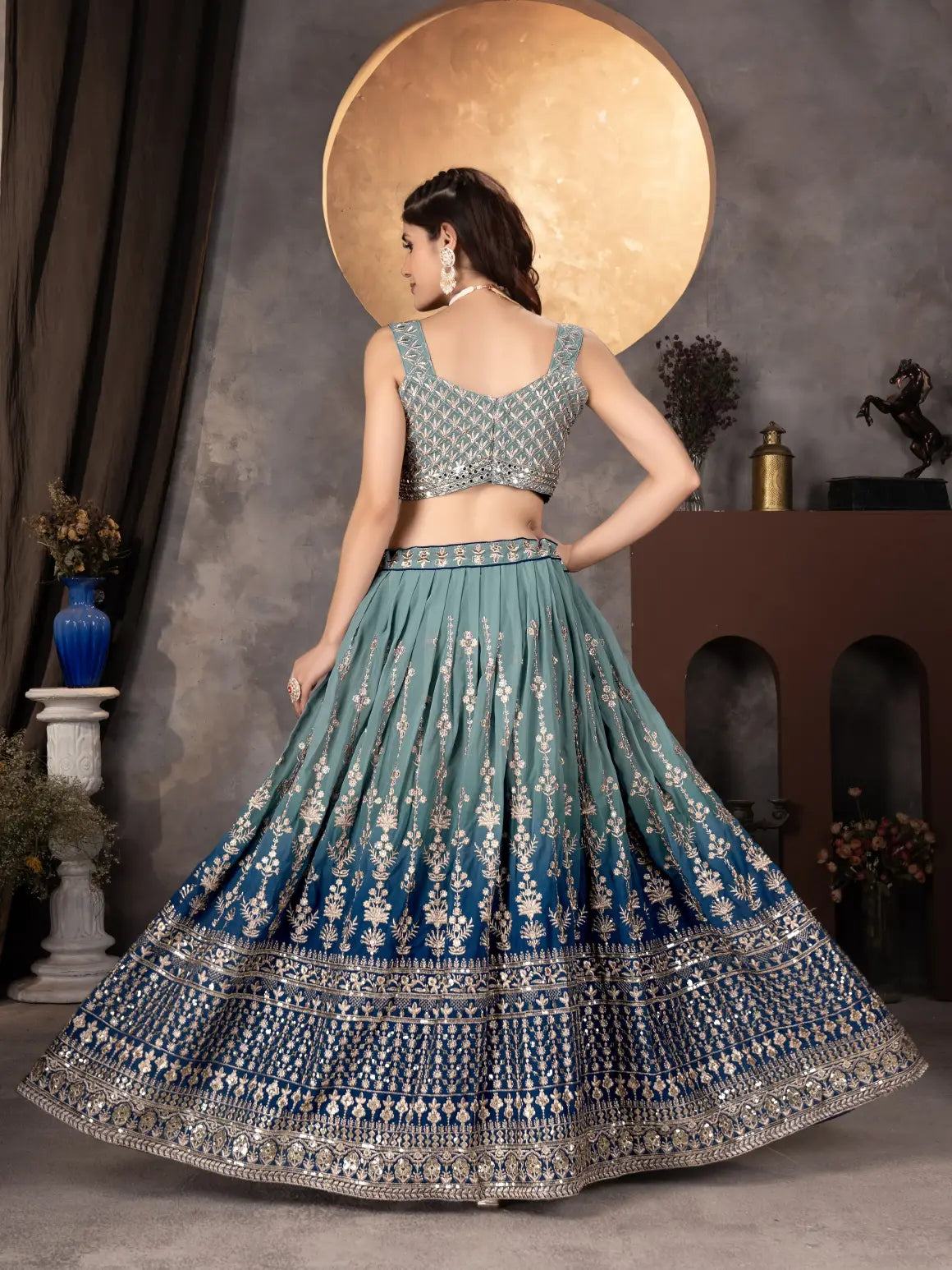 Woman in a traditional blue and silver embroidered lehenga with a neutral background