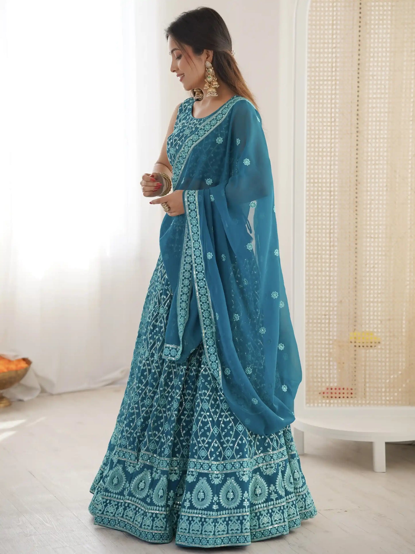 Woman wearing a blue saree with white patterns in a room.