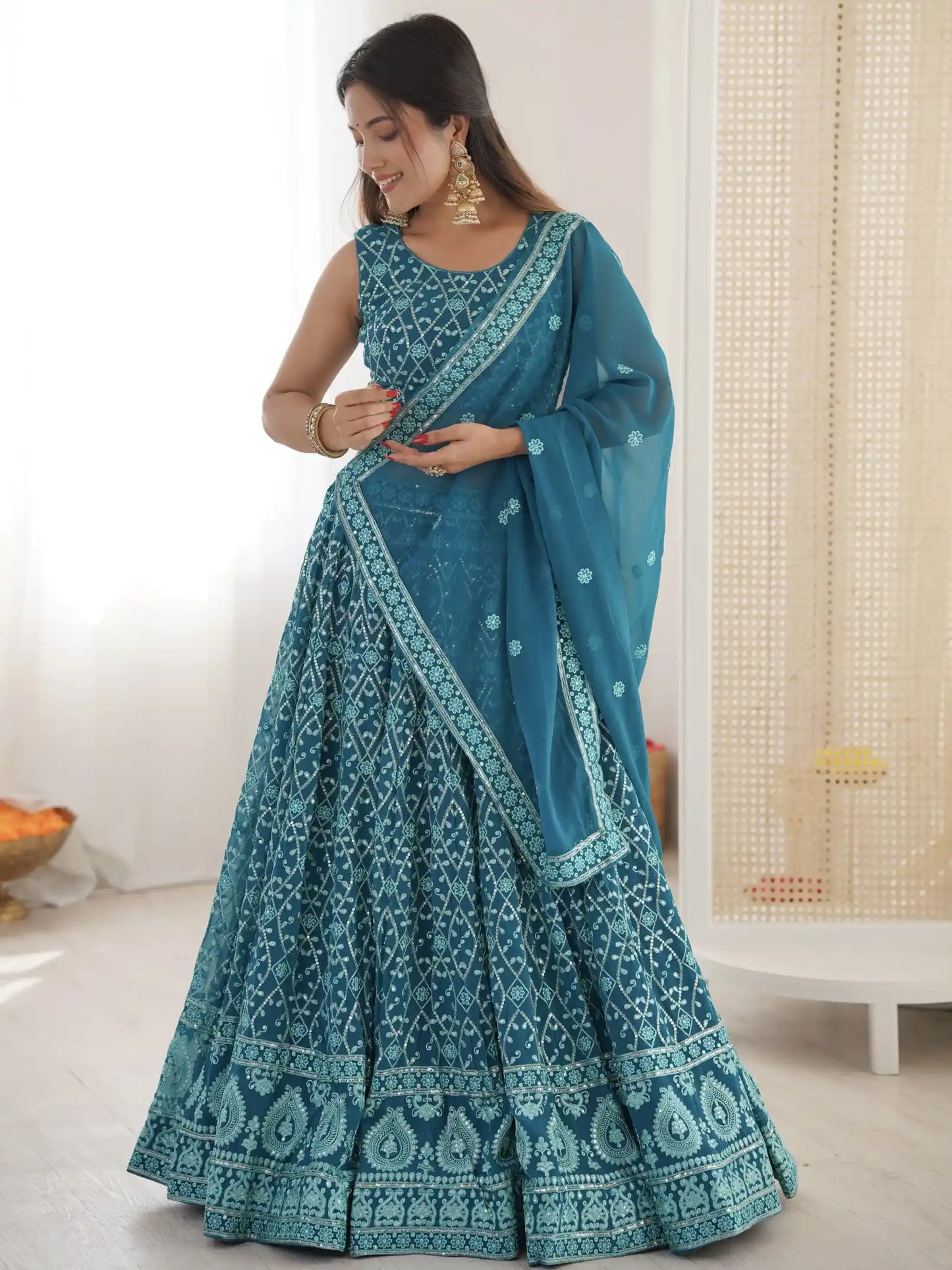 Woman wearing a blue embroidered saree in a minimal indoor setting