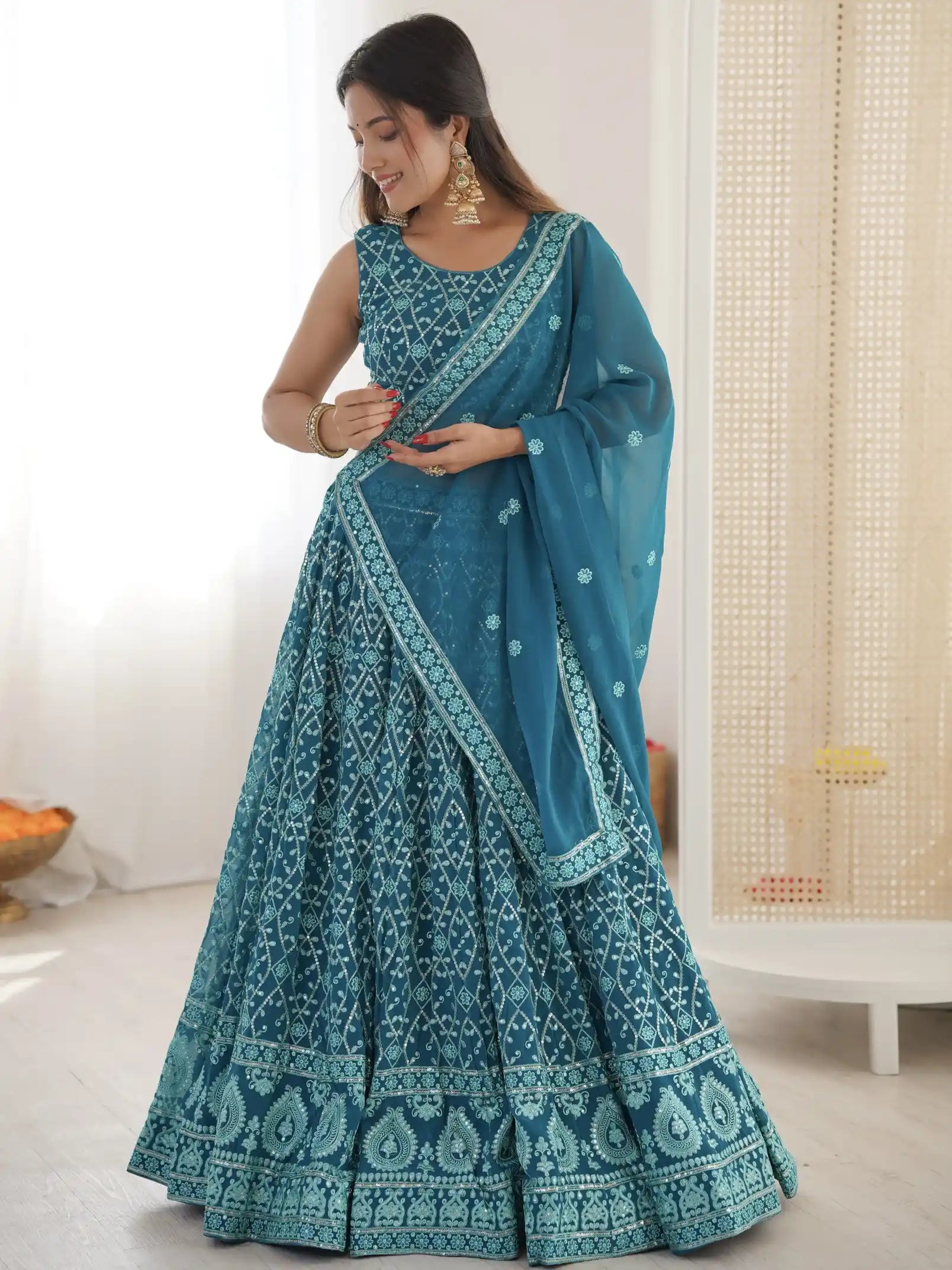 Woman wearing a blue embroidered saree in a minimal indoor setting