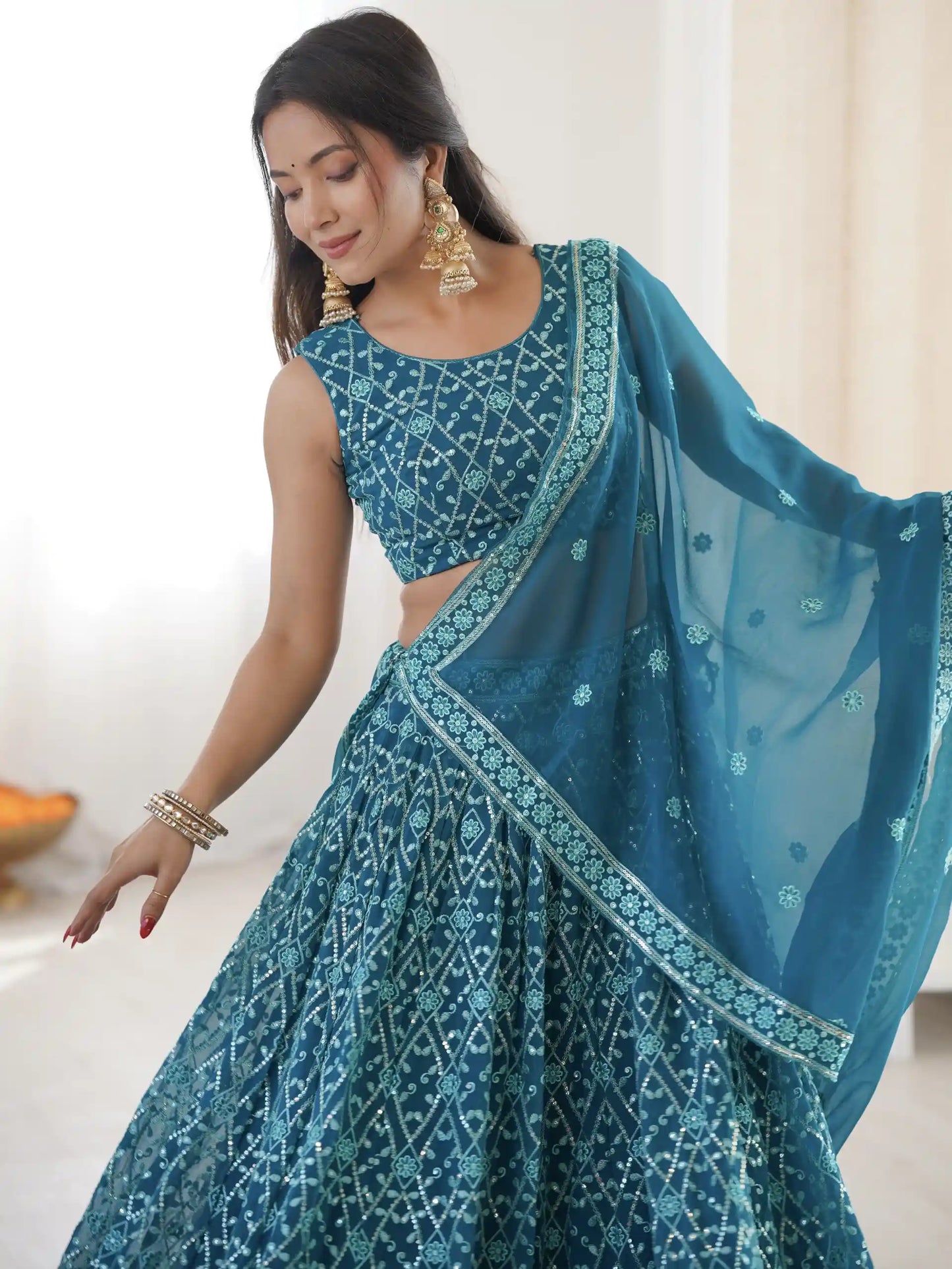 Woman wearing a blue traditional outfit with a matching dupatta indoors.