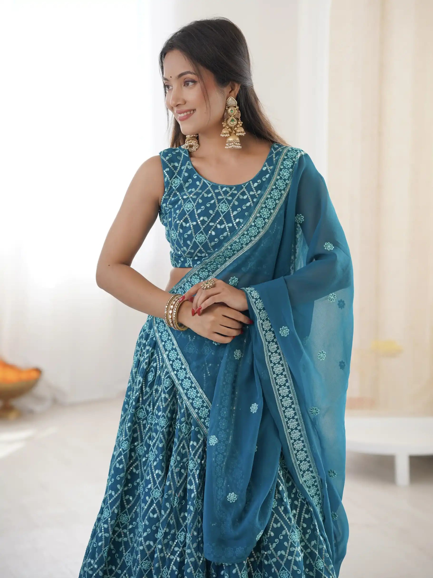 Woman wearing a blue embroidered saree in an indoor setting