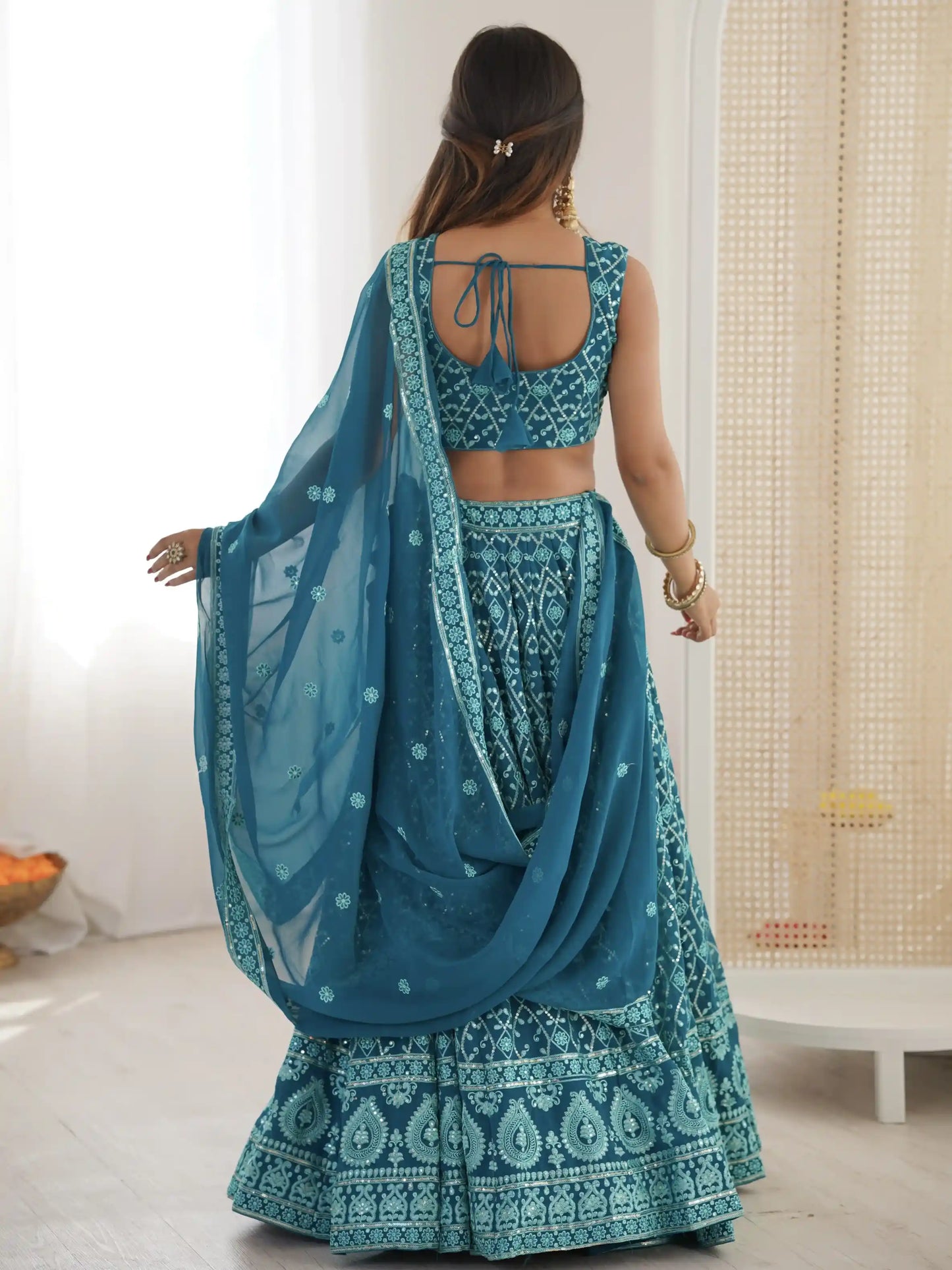 Woman wearing a blue traditional outfit with a matching dupatta in a room.