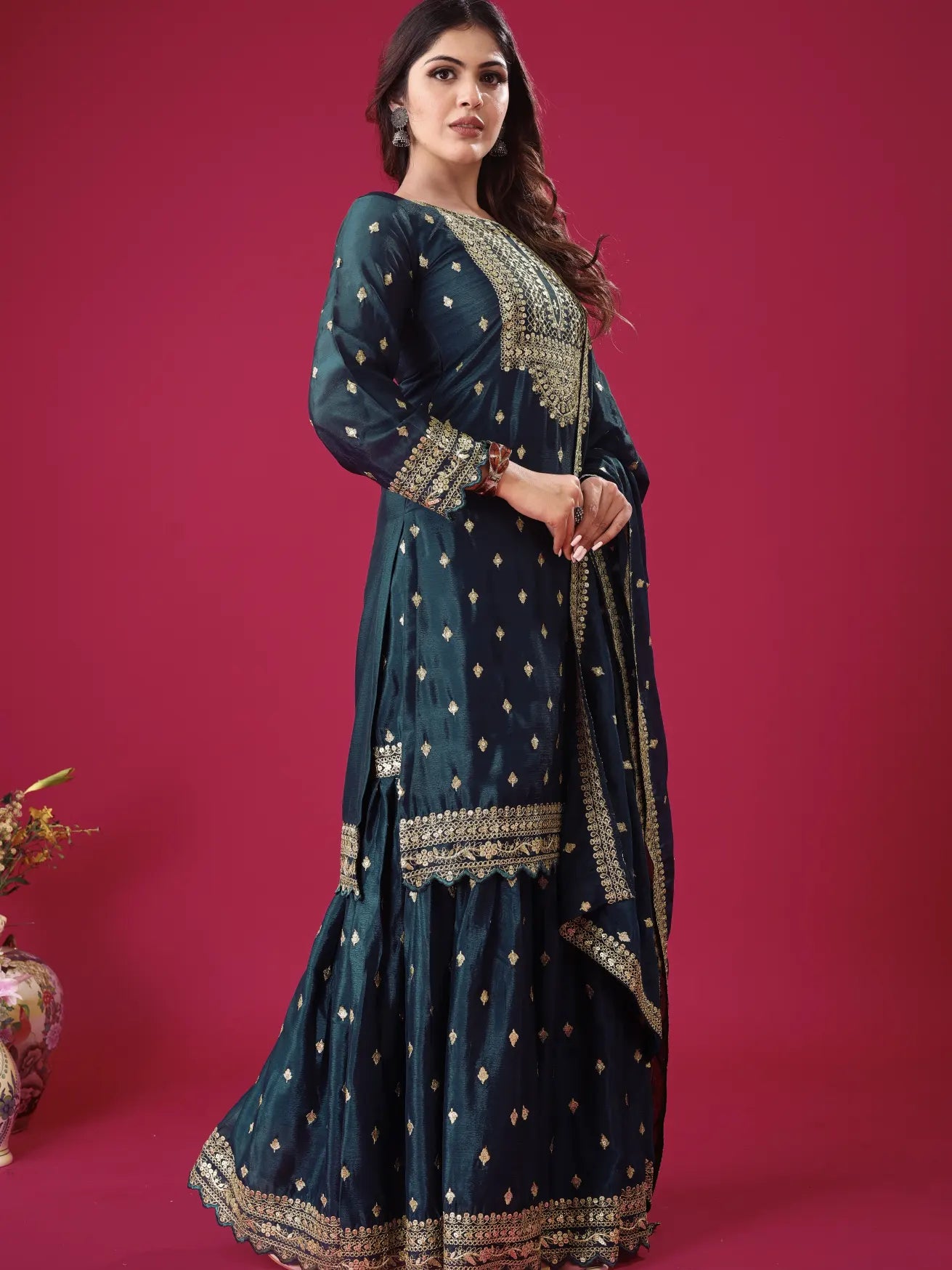 Woman wearing a dark blue embroidered traditional outfit on a pink background