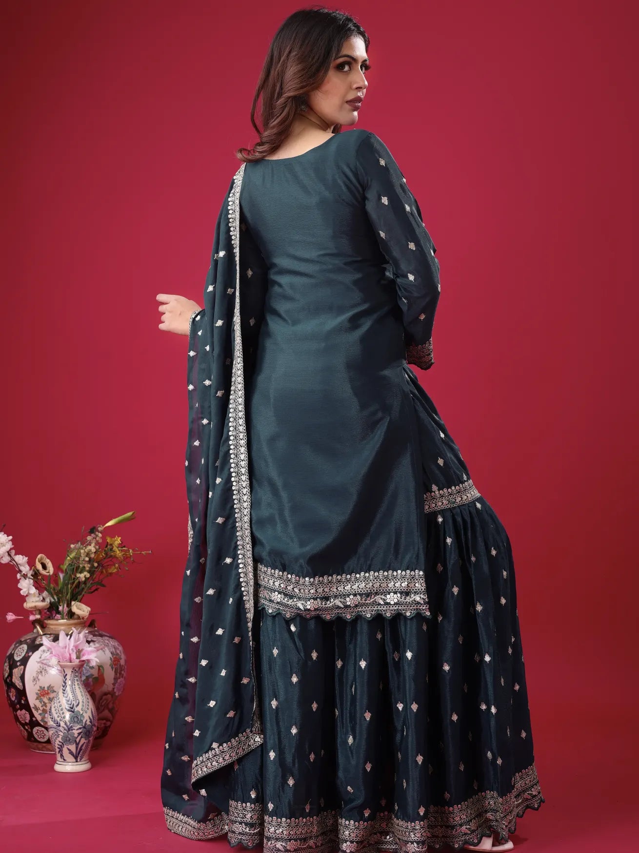 Woman in a dark green traditional outfit with white patterns on a red background