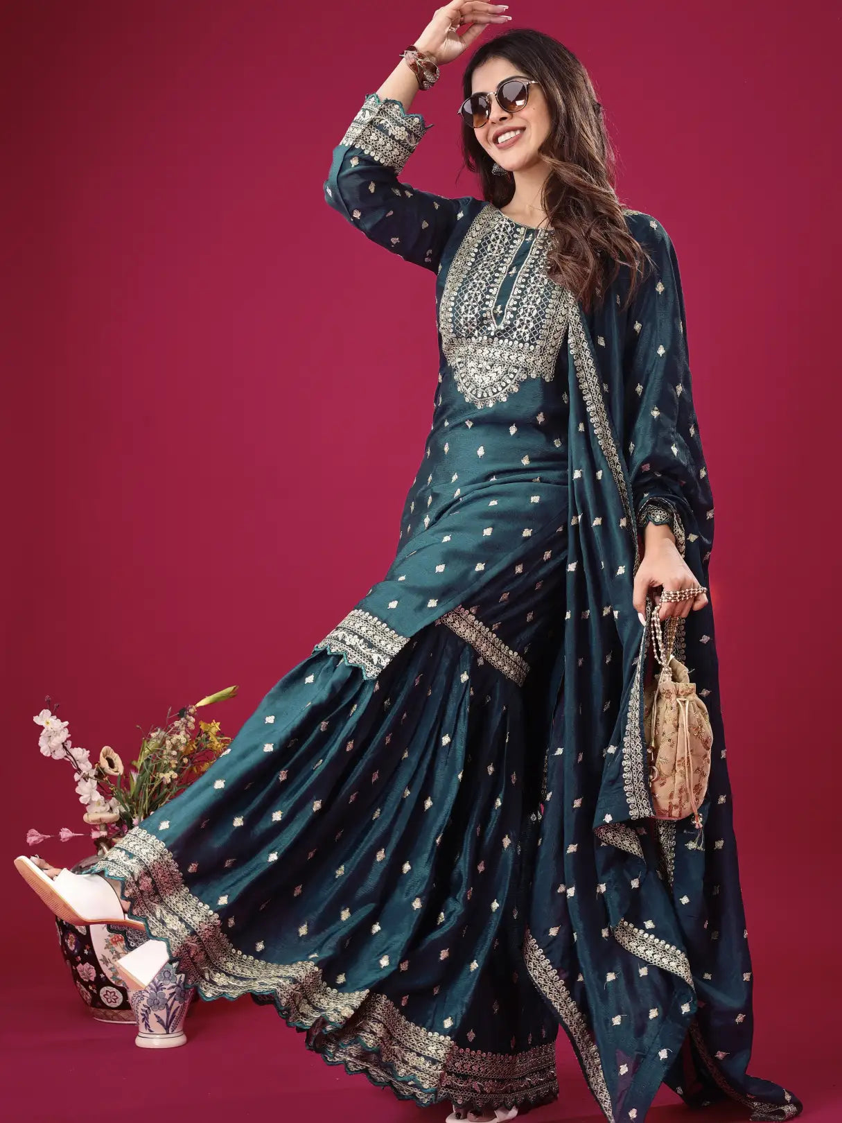 Woman in a dark blue embroidered traditional outfit on a pink background