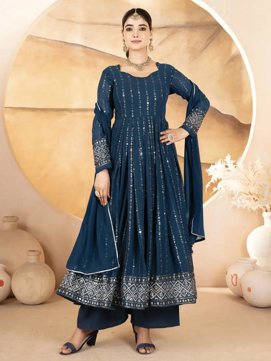 Woman wearing a blue traditional outfit with intricate patterns against a beige background