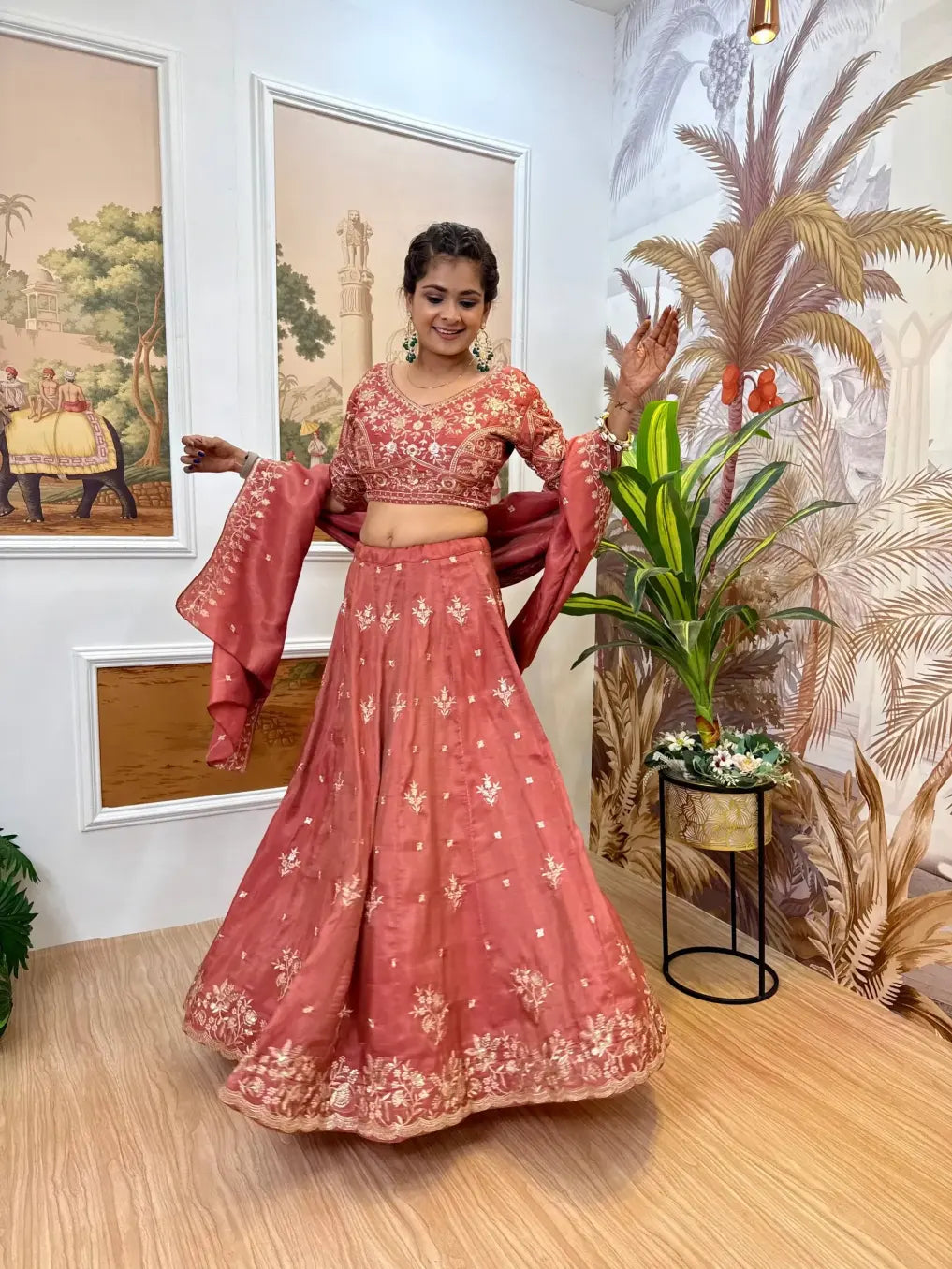 Woman in a pink traditional outfit standing in a room with decorative elements.