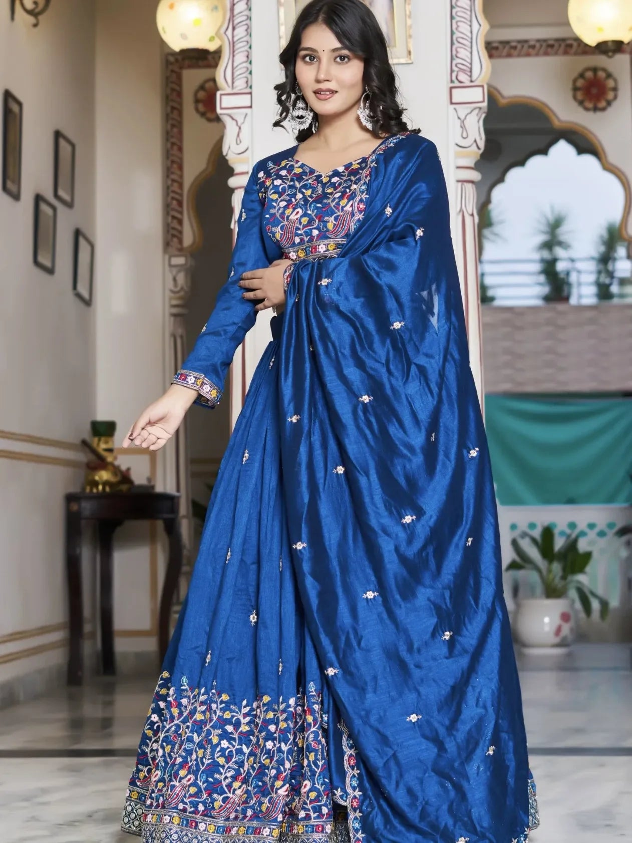 Woman wearing a blue saree with intricate patterns in an indoor setting