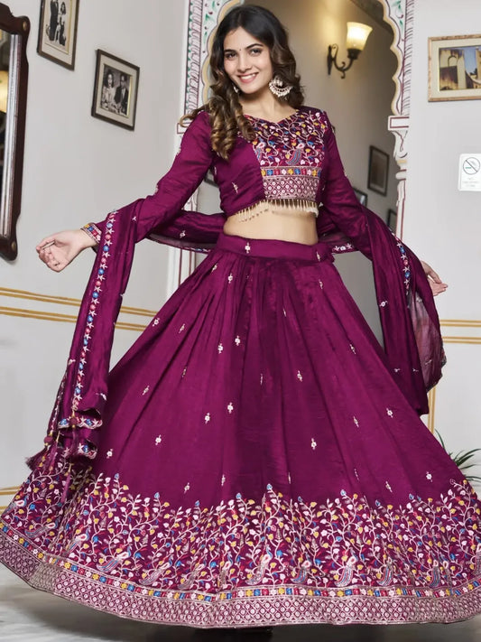 Woman wearing a purple traditional outfit with intricate designs in a decorated room.