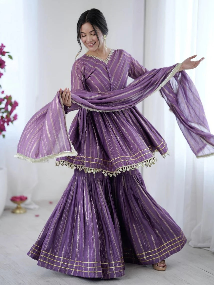 Woman wearing a purple traditional outfit with a matching dupatta in a bright setting.