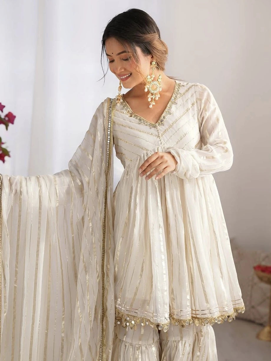 Woman wearing a traditional cream-colored outfit with gold details against a white background