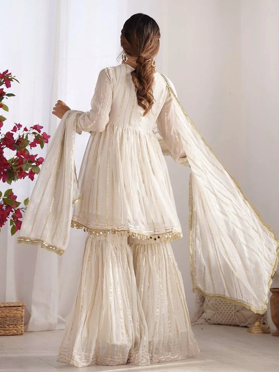 Woman wearing a traditional white outfit with a dupatta, standing against a white background.