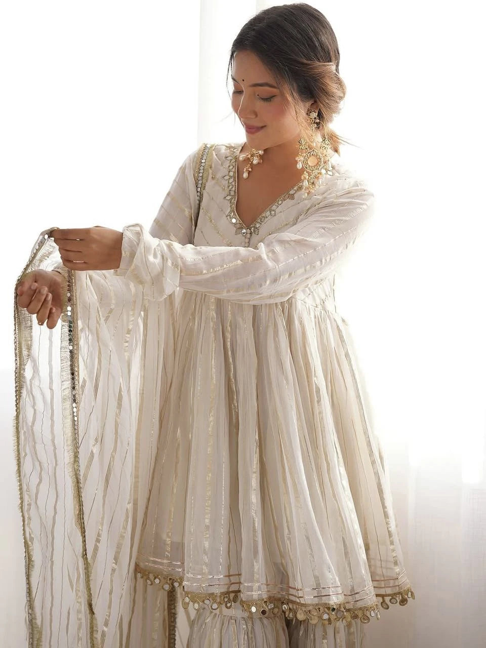 Woman wearing a traditional white outfit with gold embroidery against a white background