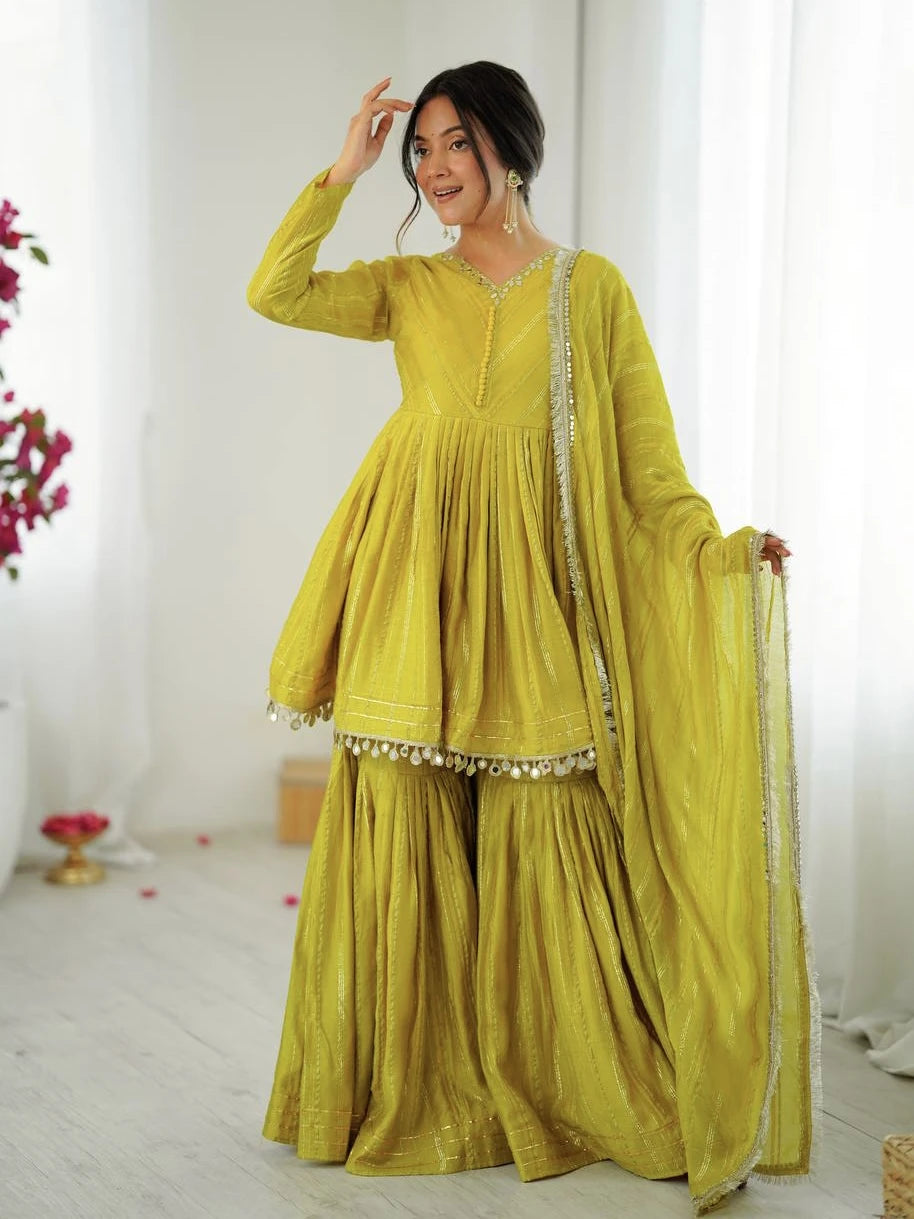 Woman wearing a yellow traditional outfit with a dupatta in a bright room.