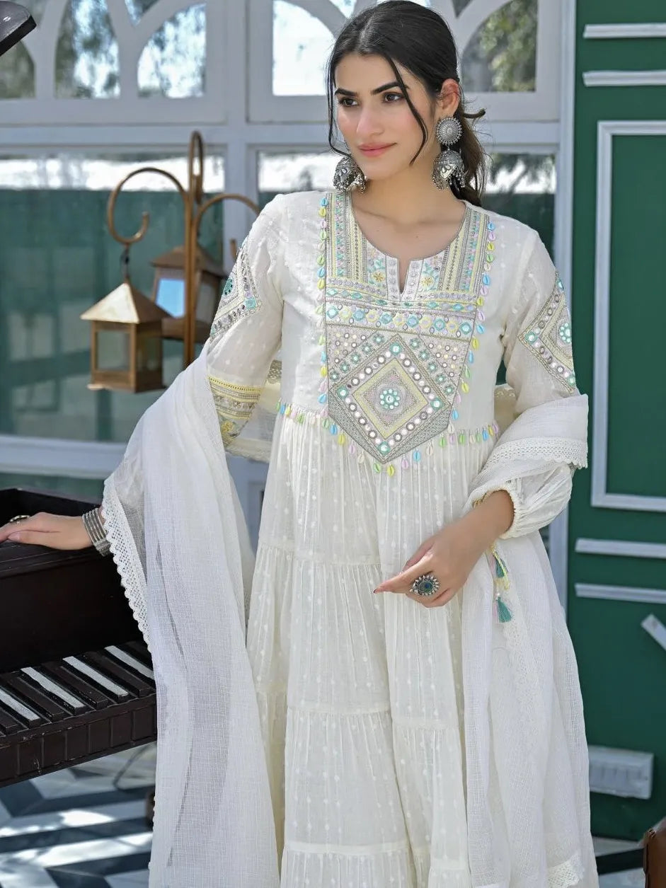 Woman wearing a white embroidered traditional outfit indoors.