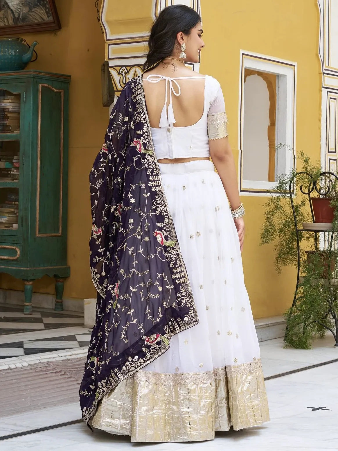 Woman in a white saree with a floral blouse in a decorated indoor setting