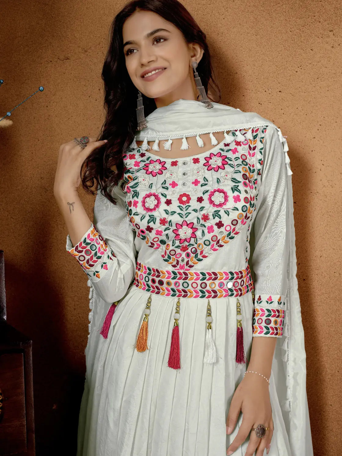 Woman wearing a traditional outfit with floral embroidery against a brown background